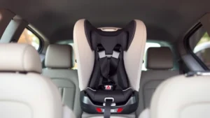 Professional photograph of a correctly installed rear-facing infant car seat in the back of a vehicle, showing proper positioning and harness adjustment, with soft natural lighting and clear view of the seat installation
